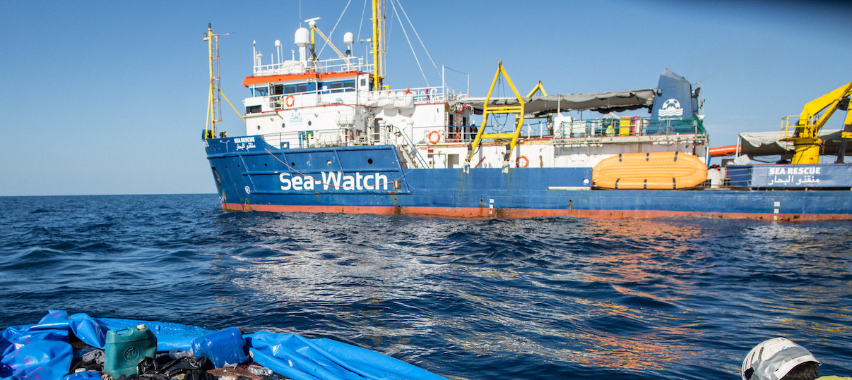 A Sea Watch 3 crew member marks with spray paint a rubber boat that the NGO destroyed after rescuing 47 migrants that were onboard, during a rescue operation by the Dutch-flagged vessel (Rear) off Libya's coasts on January 19, 2019. - The German charity group Sea Watch said on January 19 that it had rescued 47 migrants from an inflatable boat, but it was not known if they belonged to the same group that was feared missing off the Libyan coast, the International Organization for Migration said on January 19 after the Italian navy flew three survivors to the Mediterranean island of Lampedusa. (Photo by FEDERICO SCOPPA / AFP)        (Photo credit should read FEDERICO SCOPPA/AFP/Getty Images)