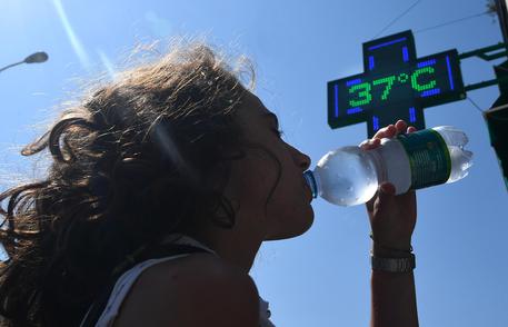 Una ragazza si disseta bevendo acqua fredda da una bottiglietta a Genova. 31  luglio 2018. Ondata di calore in Liguria con bollino rosso anche per il 2 agosto, prolungata dunque di altre 24 ore dal Ministero di Salute rispetto all'allerta diramato ieri. Arpal ha emesso un avviso meteorologico per avvertire dell'ondata di calore con elevato disagio a causa di temperature elevate e tassi d'umidità medio alti.    ANSA/LUCA ZENNARO